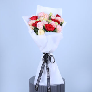 Mixed flower bouquet of roses, and carnations, in shade of pink and red.