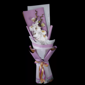 A bouquet of white orchids wrapped in pink and brown paper with a golden ribbon.