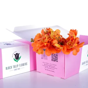 A bunch of vibrant orange flowers, possibly orchids, are spilling out of the open top box.