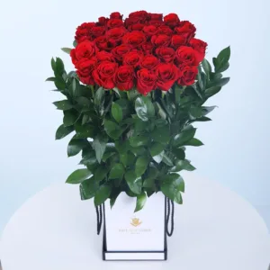A charming box filled with Red Roses and a lush bunch of Ruscus leaves.