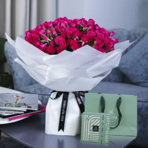 A bouquet of vibrant pink roses with patchi chocolate