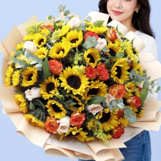 Fresh floral bouquet featuring bright sunflowers, orange roses, light pink roses, eucalyptus leaves, and solidaster arranged in a warm hand-tied style
