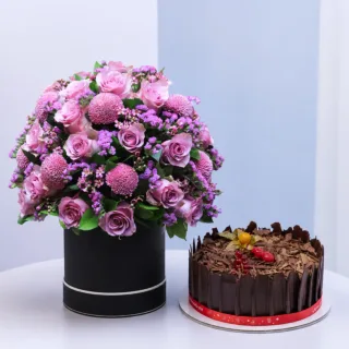 Luxury bouquet of purple roses and pink flowers with fillers and greenery combined with a Black Forest Cake for celebration gifting
