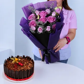 Stylish floral arrangement of roses in purple and pink tones with fillers paired with a 1 kg Black Forest Cake for celebrations
