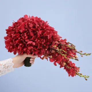Luxurious red orchid cascade bridal bouquet with trailing blooms, designed for modern brides seeking a bold yet elegant floral accessory.