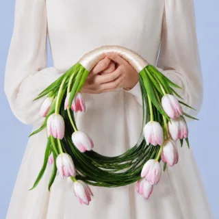 Romantic bridal bouquet with pastel pink tulips and artistic steel grass accents for chic wedding aesthetics.