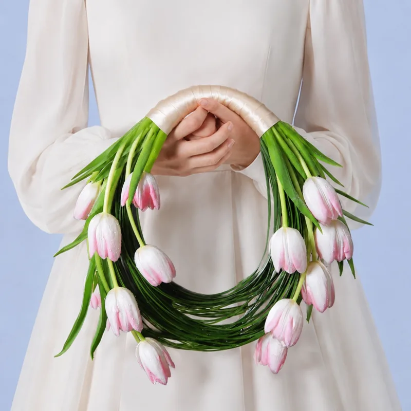 Romantic bridal bouquet with pastel pink tulips and artistic steel grass accents for chic wedding aesthetics.