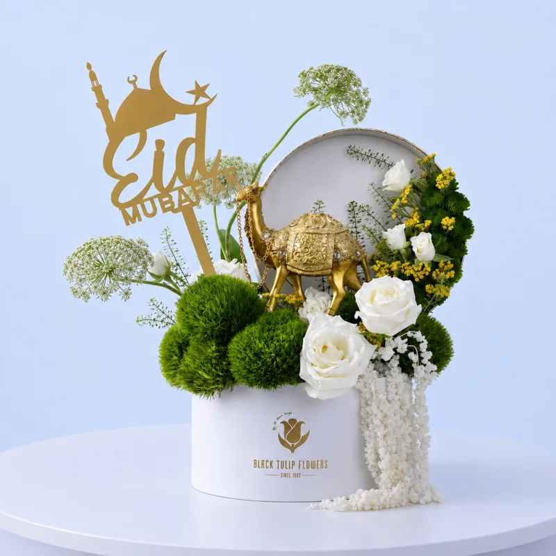 white-rose-eid-gift-box_01_01 Elegant Eid special floral gift box featuring fresh white roses, lush green foliage, and a decorative camel figurine, symbolizing purity, peace, and festive celebration.