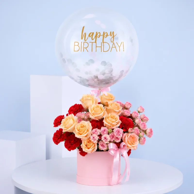 birthday-flower-box-arrangement Elegant birthday gift flower box containing peach roses, red carnations, pink spray roses, and a happy birthday balloon.