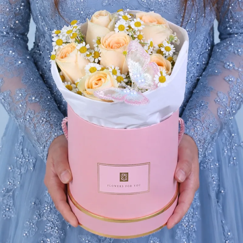 peach-rose-butterfly-gift-box A peach rose gift box with delicate white flowers and a butterfly gently placed among the blooms, creating a soft and elegant floral arrangement.
