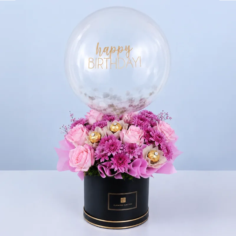 pink-delight-ferrero-bouquet-and-balloon Pink-themed bouquet in a black round box featuring roses, chrysanthemums, Ferrero Rocher chocolates, and a balloon arranged as a luxurious celebration gift.