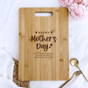light brown wooden cutting board with rounded corners and a handle cutout at the top is positioned on a wrinkled white cloth.