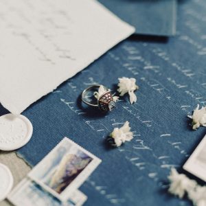 This is a close-up shot of various stationery items and a ring, possibly arranged for a wedding or romantic theme