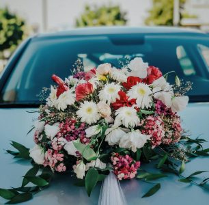 a white car adorned with a floral arrangement on its hood